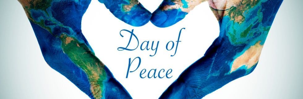Hands painted with a world map forming a heart shape, centered around the text "Day of Peace," symbolizing global unity and climate awareness.